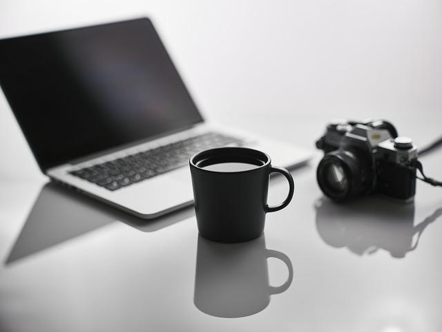 laptop, camera and mug on table. 